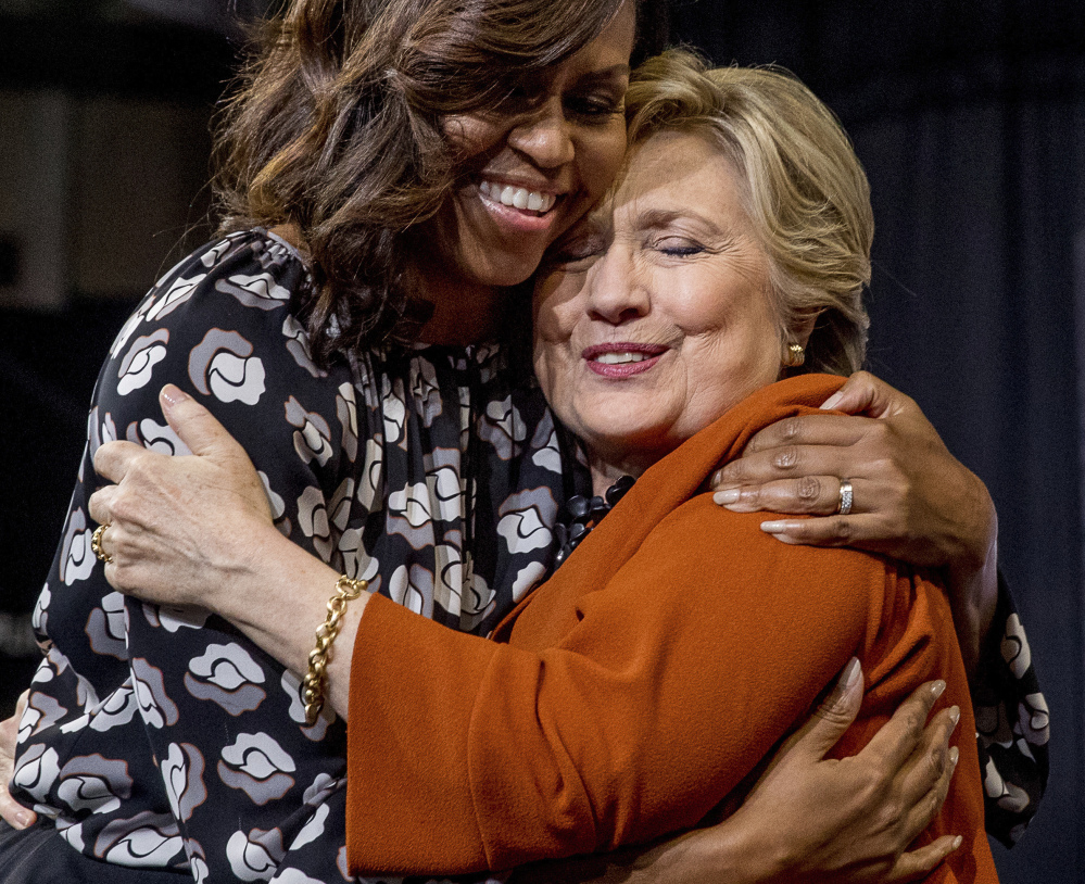 First lady Michelle Obama and Democratic presidential candidate Hillary Clinton hug after speaking at a campaign rally in Winston-Salem, N.C., on Thursday. Even as they urged their audience to resist Republican attempts to convince them to stay home on Election Day, Republican nominee Donald Trump was in Ohio suggesting to his fans that the election be scrapped and given to him.