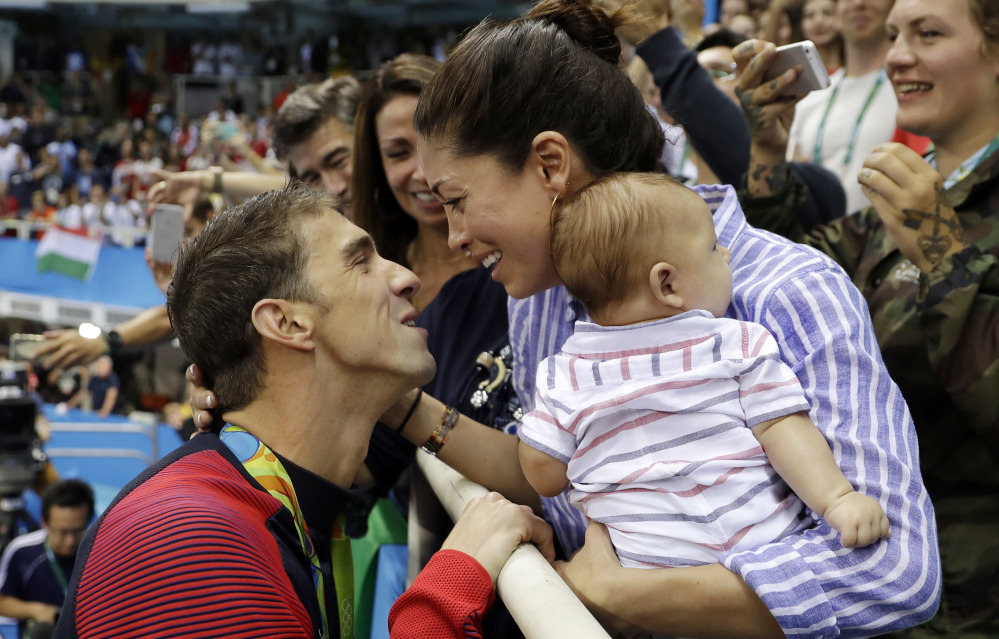 Swimmer Michael Phelps celebrates winning his gold medal in the men's 200-meter butterfly with Nicole Johnson and baby Boomer during the Rio Olympics.