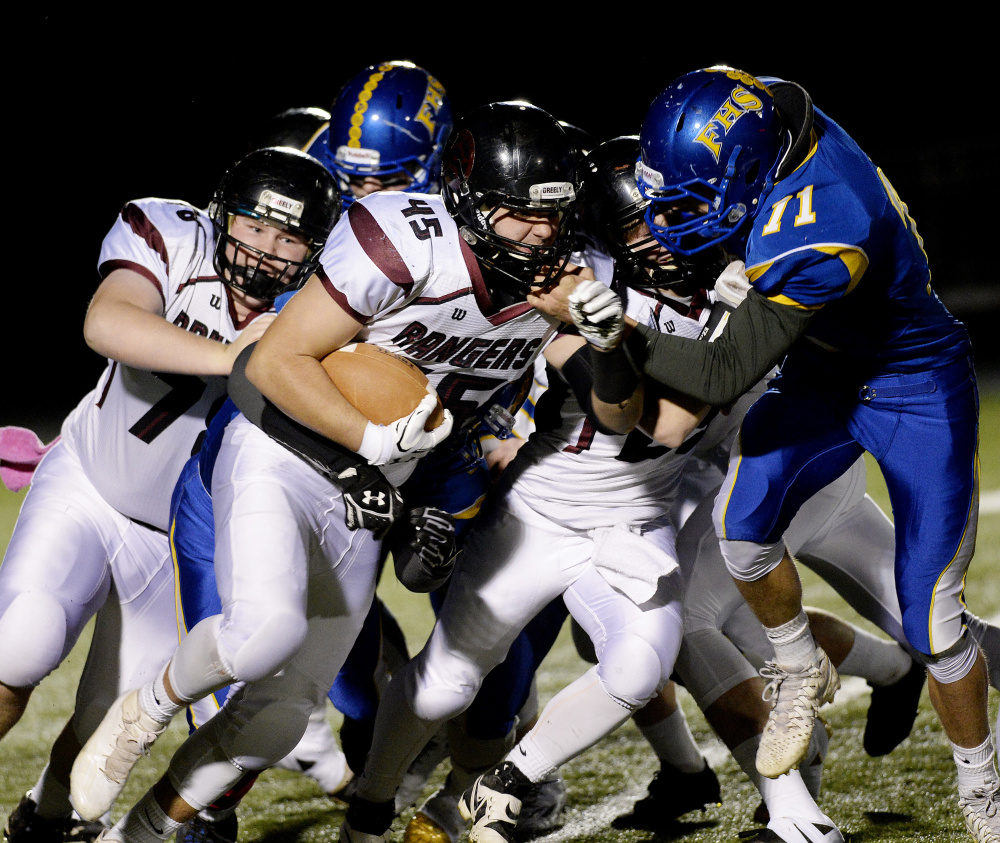 Greely's Tim Coyle looks for running room and gets a push from a teammate as Falmouth's Griffin Aube moves in for the tackle during their Class B South quarterfinal Friday night in Falmouth. After losing to the Yachtsmen a week earlier, Greely advanced to the semifinals with a 20-7 win.