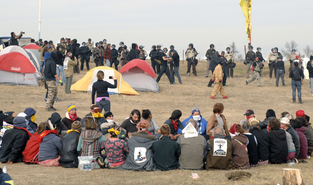 Dakota Access pipeline protesters sit in a prayer circle as law enforcement officers make their way across the camp to remove them in North Dakota on Thursday.