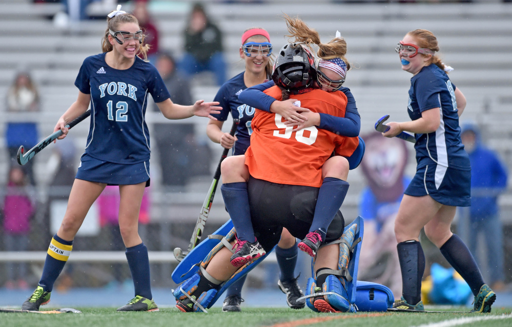 York High's Sydney Bouchard jumps in to the arms of goalie Julia Carr after the Wildcats defeated Belfast, 2-1, in the Class B field hockey state championship game in Bath on Saturday.