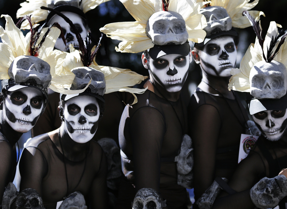 Men wait for a Day of the Dead parade to begin in Mexico City on Saturday. Traditional celebrations are changing under the influence of Hollywood movies.