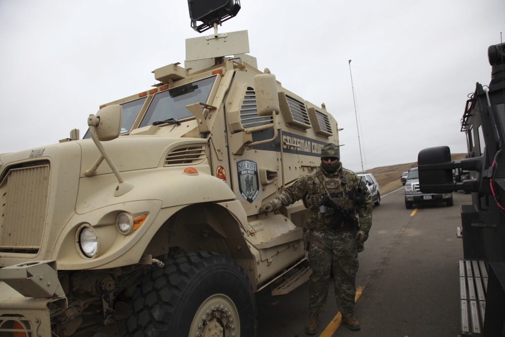 A member of the Stutsman County SWAT team stands guard by an armored personnel carrier equipped with a long range acoustic device, while deployed to watch protesters demonstrating against the Dakota Access pipeline in Cannonball, N.D., on Sunday.