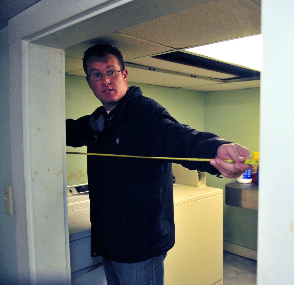 City of Augusta Code Enforcement Officer Robert Overton measures a doorway during an Oct. 2 inspection of an apartment building.