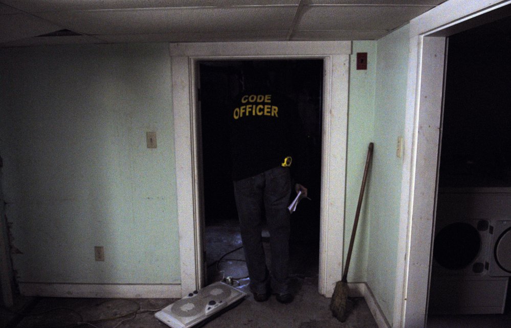 City of Augusta Code Enforcement Officer Robert Overton looks around in a basement during an inspection on Oct. 2 of an apartment building.