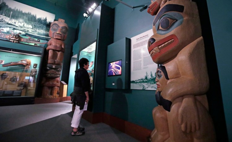 A visitor stands among totem poles as she watches a video as part of Hall of the North American Indian exhibit, at the Peabody Museum of Archaeology & Ethnology at Harvard University in Cambridge, Mass., Thursday, Oct. 13, 2016. The Peabody, one of the oldest and largest museums in the world focused on the study of societies and cultures, turns 150 years old this month.