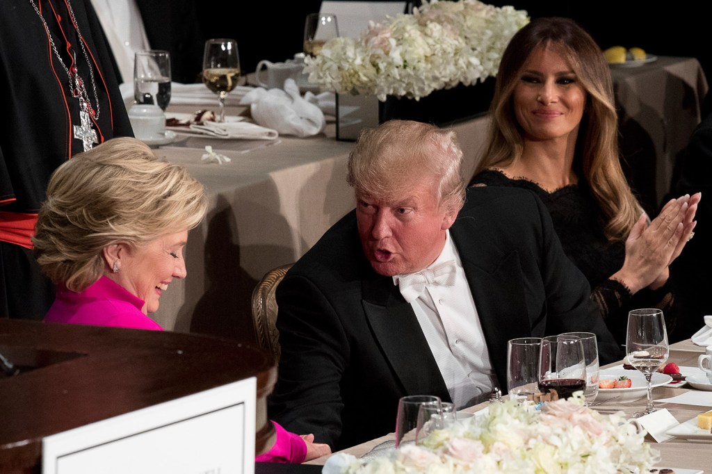 Republican presidential candidate Donald Trump, center, accompanied by his wife Melania Trump, right, shakes hands with Democratic presidential candidate Hillary Clinton at the 71st annual Alfred E. Smith Memorial Foundation Dinner on Oct. 20 in New York. The dinner is supposed to be a gentle roast at which political foes parry a bit but always with rubber rapiers.