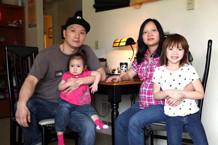 Korean adoptee Adam Crapser, left, poses with daughters, Christal, 1, Christina, 5, and his wife, Anh Nguyen, in the family's living room in Vancouver, Wash. in 2015.
