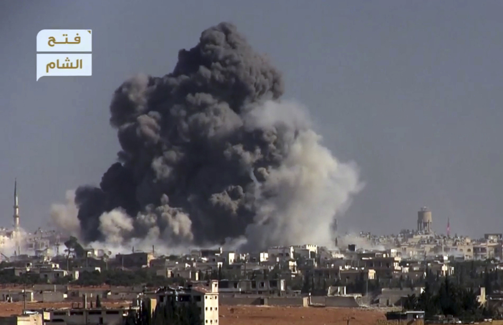 This frame grab from video provided by this militant video by Fatah al-Sham Front that is consistent with independent Associated Press reporting, shows black smoke rising from a suicide bomb attack on Syrian government forces positions in western Aleppo, Syria, Thursday. The Britain-based Syrian Observatory for Human Rights, which monitors the conflict through local contacts, reported that rebels attacked government positions with two explosives-laden vehicles. Syrian rebels launched a fresh wave of attacks on western districts of Aleppo Thursday as airstrikes on a rebel-held village south of the contested city killed civilians, activists said.