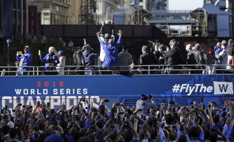 Chicago Cubs' Dexter Fowler hoists the championship trophy during a parade honoring the World Series champion Chicago Cubs baseball team on Friday in Chicago.