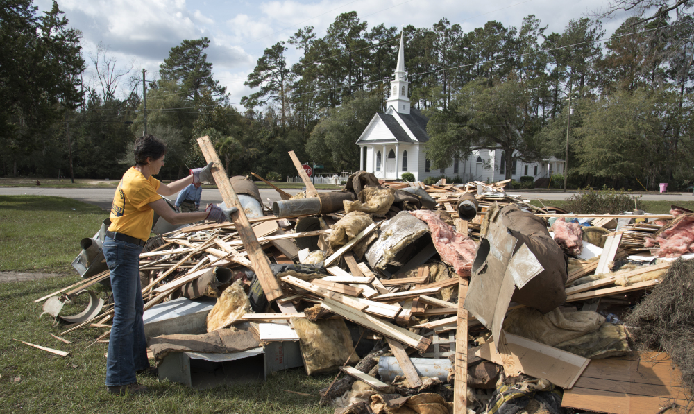 Wendy Gable, with Southern Baptist Convention Disaster Relief, throws wood on a pile from a home that was heavily damaged by floodwaters from Hurricane Matthew in Nichols, S.C.