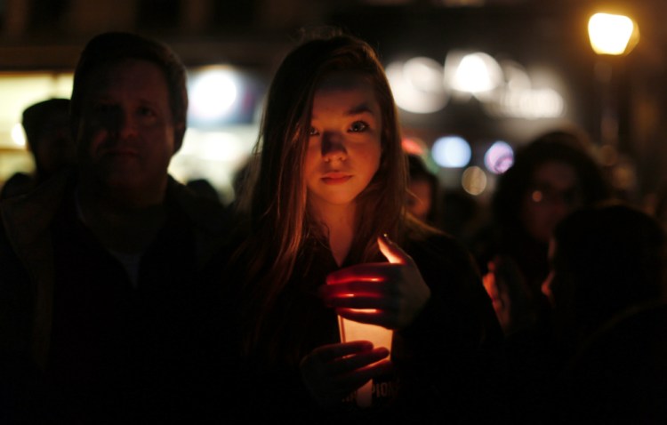 Portland resident Hannah Elizabeth Little holds a candle amid a crowd of hundreds of participants in Monument Square in Portland during a vigil to pledge unity Wednesday.