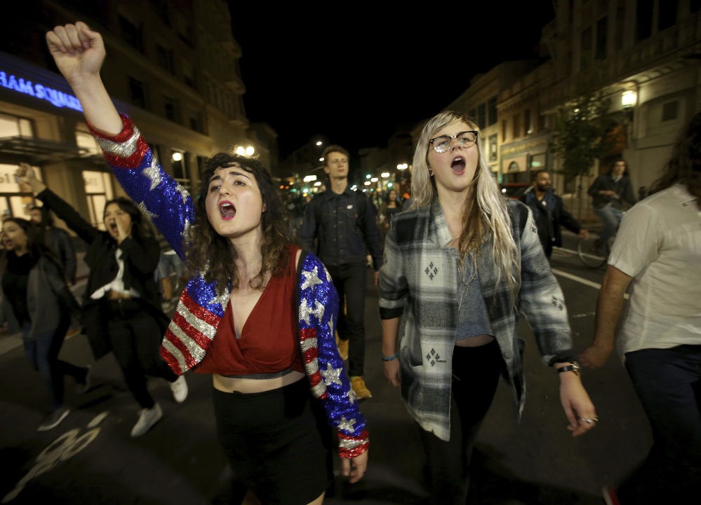 Madeline Lopes, left, and Cassidy Irwin, both of Oakland, Calif., march with other protesters in downtown Oakland early Wednesday in one of several demonstrations across the country.