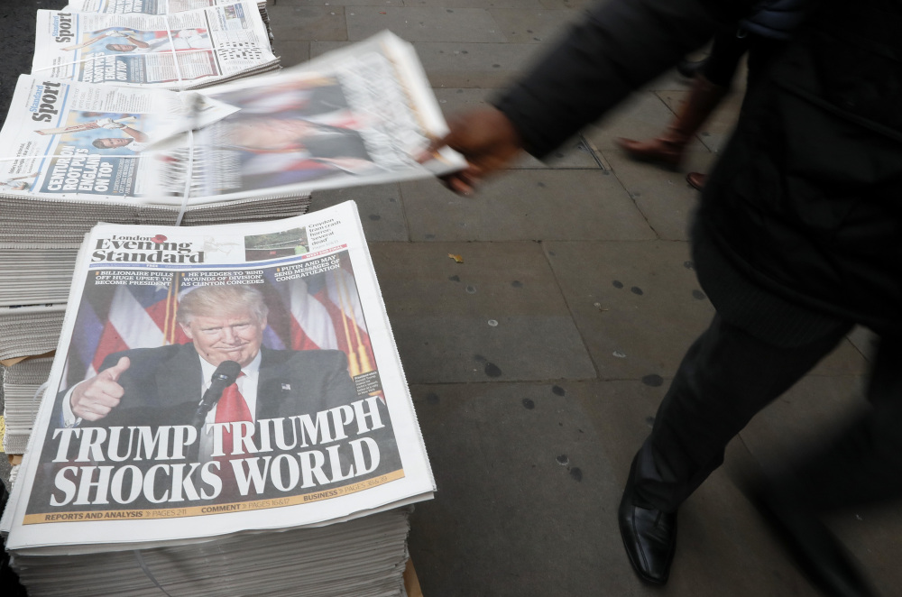 A passer-by takes a copy of the Evening Standard, the local free newspaper in London. NATO allies now wonder whether Donald Trump will keep his pledge on conditional protection.