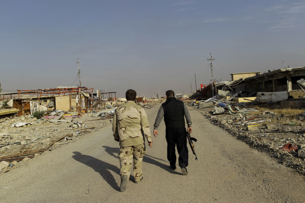 Ali Hussein, right, and his son walk to check on the family's used car business, which was looted by Islamic State fighters and destroyed in fighting to oust them in Bashiqa, east of Mosul, Iraq, on Friday. 