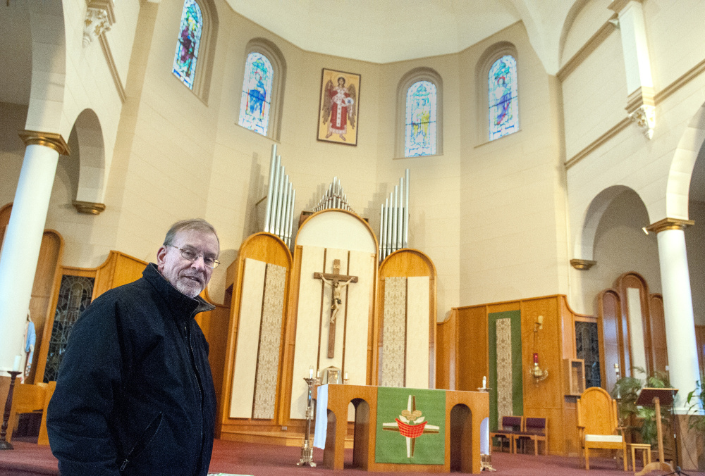 The Rev. Frank Morin stands in front of the altar Friday at St. Augustine Church in Augusta. The parish is celebrating the centennial of the opening of the church building.
