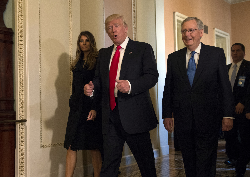 President-elect Donald Trump, accompanied by his wife, Melania, and Senate Majority Leader Mitch McConnell of Ky., walks on Capitol Hill in Washington.