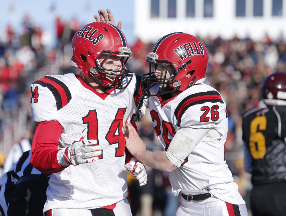 Riley Dempsey of Wells gives his teammate Jordan Cluff a pat on the helmet after Cluff picked up a big first down in the fourth quarter of Saturday's regional championship game at Cape Elizabeth. Wells was motivated by losses in the regional finals in the last two seasons.