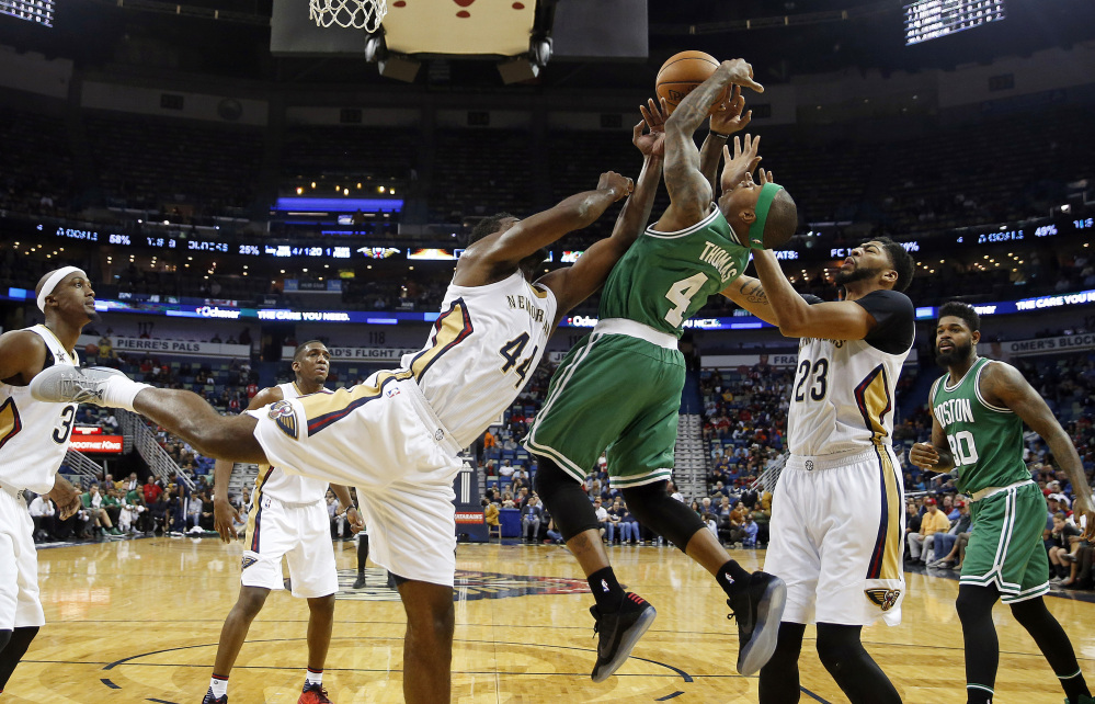 Celtics guard Isaiah Thomas battles under the basket with Pelicans forwards Anthony Davis (23) and Solomon Hill (44) in the first half of Monday night's game in New Orleans