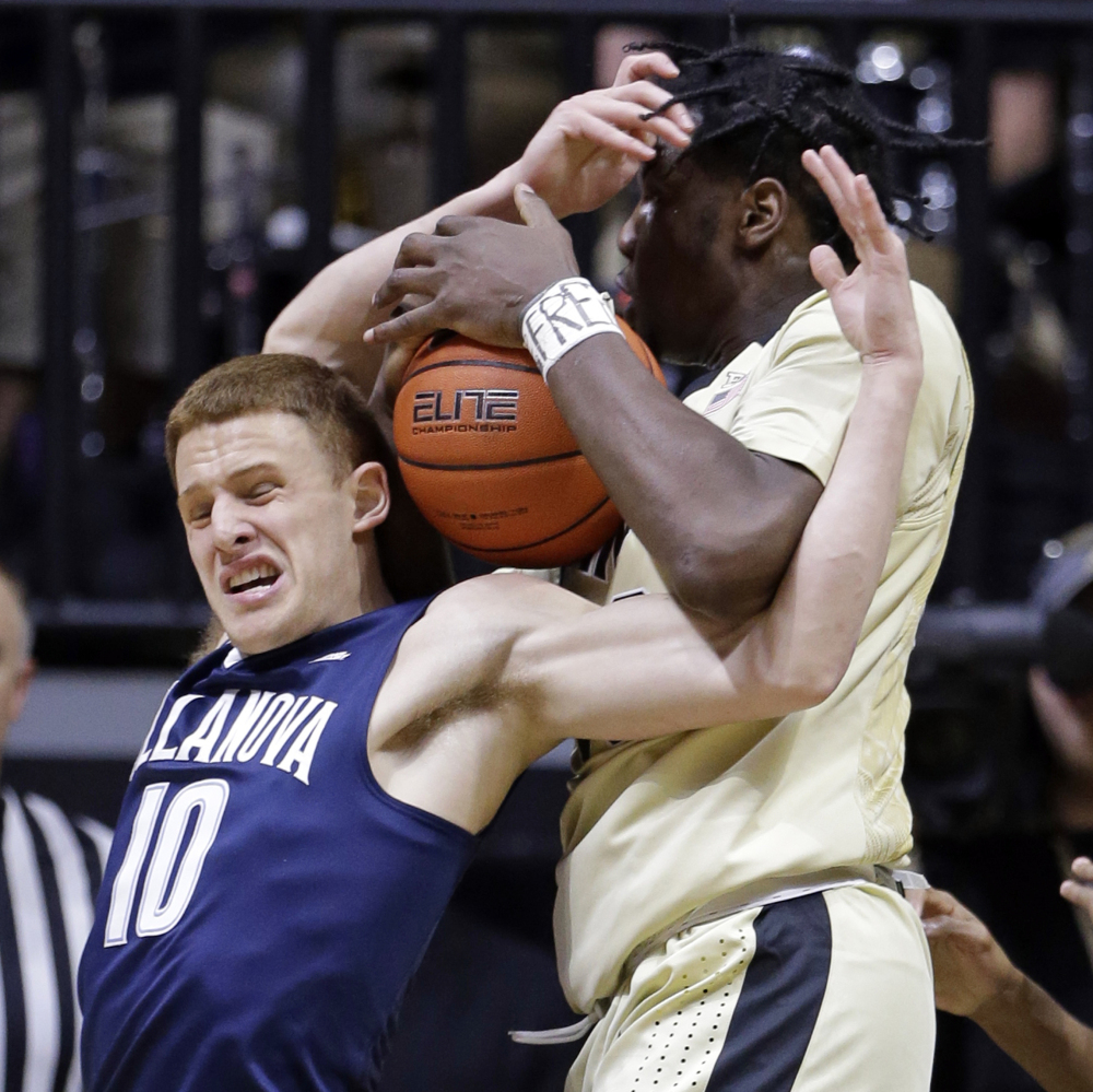 Purdue forward Caleb Swanigan, right, and Villanova guard Donte DiVincenzo battle for the ball in the first half of a 79-76 win by the Wildcats at West Lafayette, Ind., on Monday.