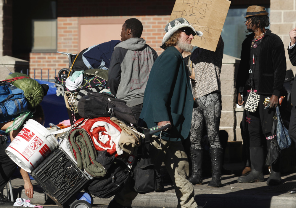 A man drags his belongings during a police sweep of homeless people living on the sidewalks near a shelter in downtown Denver on Tuesday.