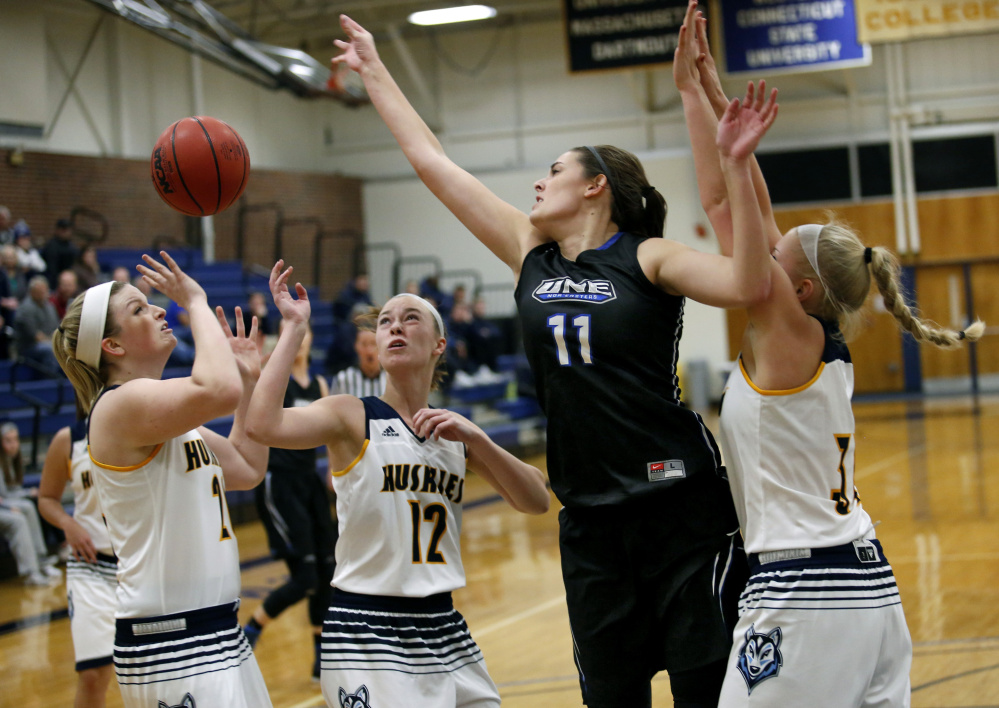 Alicia Brown of the University of New England, 11, battles for control of the ball with Kimberly Howrigan, left, Emily Nicholson and Chantel Eells, right, of USM during the first half of UNE's 62-46 victory in a women's basketball opener Tuesday night.