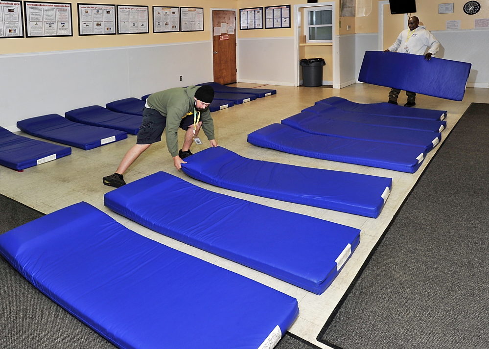Brian Marchant, left, and Bonane Rutijanwa, attendants at the municipal homeless shelter in Portland, set up mats in a city office in 2013 for use if shelter space was filled. Historically, only about a third of clients at the shelter are Portland residents.
