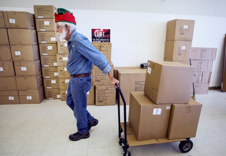 Carl Akin of Yarmouth, who is volunteering for his sixth year, moves boxes of packaged toys at the Toy Fund's processing center in Falmouth on Thursday.
