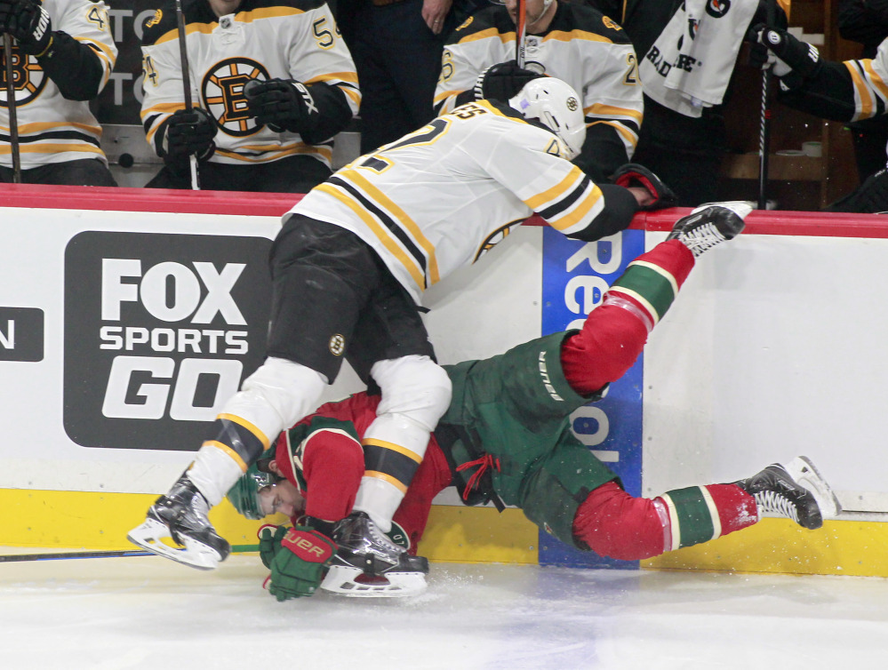 Minnesota's Nino Niederreiter is checked hard into the boards by Boston's David Backes in the first period Thursday night in St. Paul, Minn.