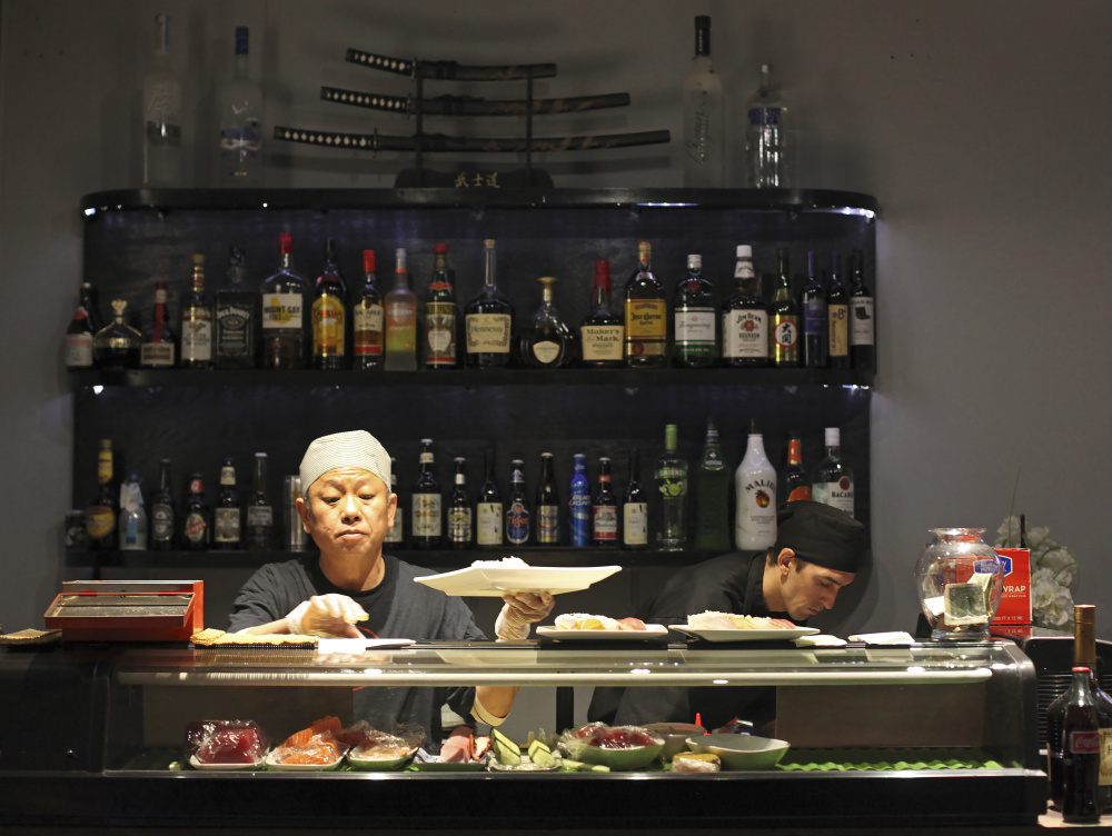Duc Bui, owner and head sushi chef at Ginza Town, and Rick Roy, sushi chef, at work during the dinner hour.