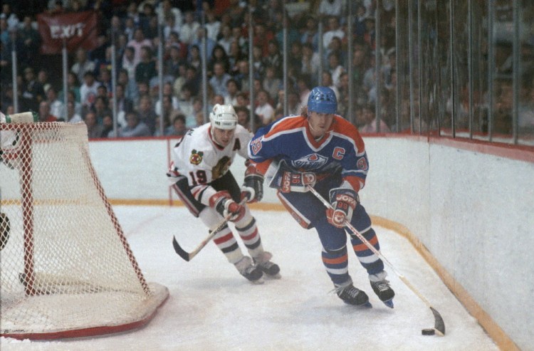 Edmonton Oilers'  Wayne Gretzky (99) carries the puck behind the net in a game against the Chicago Black Hawks in 1987. Gretzky will lend his voice to a character in 'The Simpsons.'