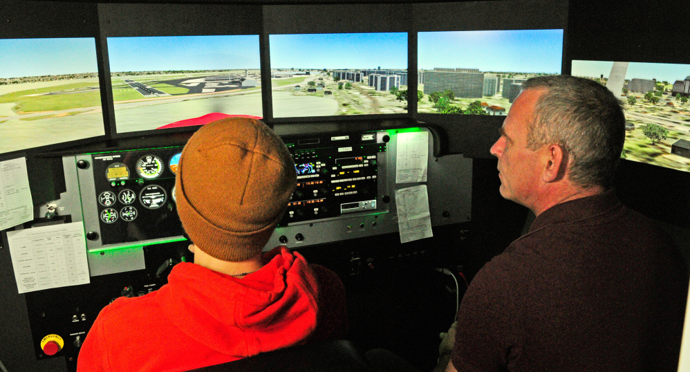 Maranacook Community High School student Tanner Evans, left, tries out the flight simulator with instructor David Russo on Friday at the University of Maine at Augusta.