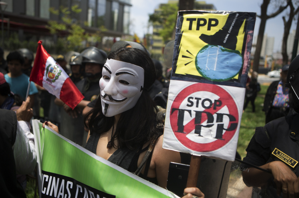 A protester holds signs against the Trans-Pacific Partnership during a rally in November in Lima, Peru.