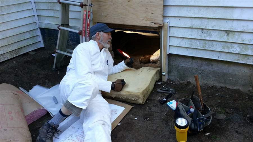 Dave Brown, 75, a volunteer for the Harpswell Aging at Home team, insulates the floor under a house in coastal Maine. Volunteers in the graying state are helping seniors remain in their homes.