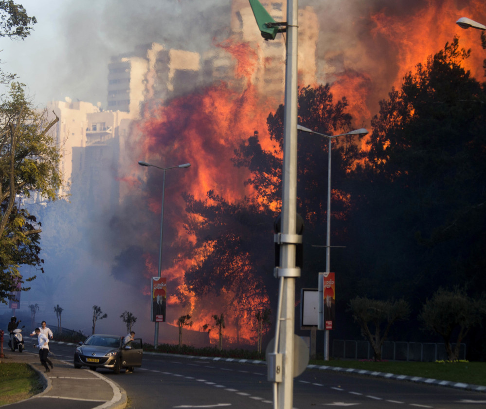 People run from flames in Haifa on Thursday as fire spreads through Israel's third-largest city. 