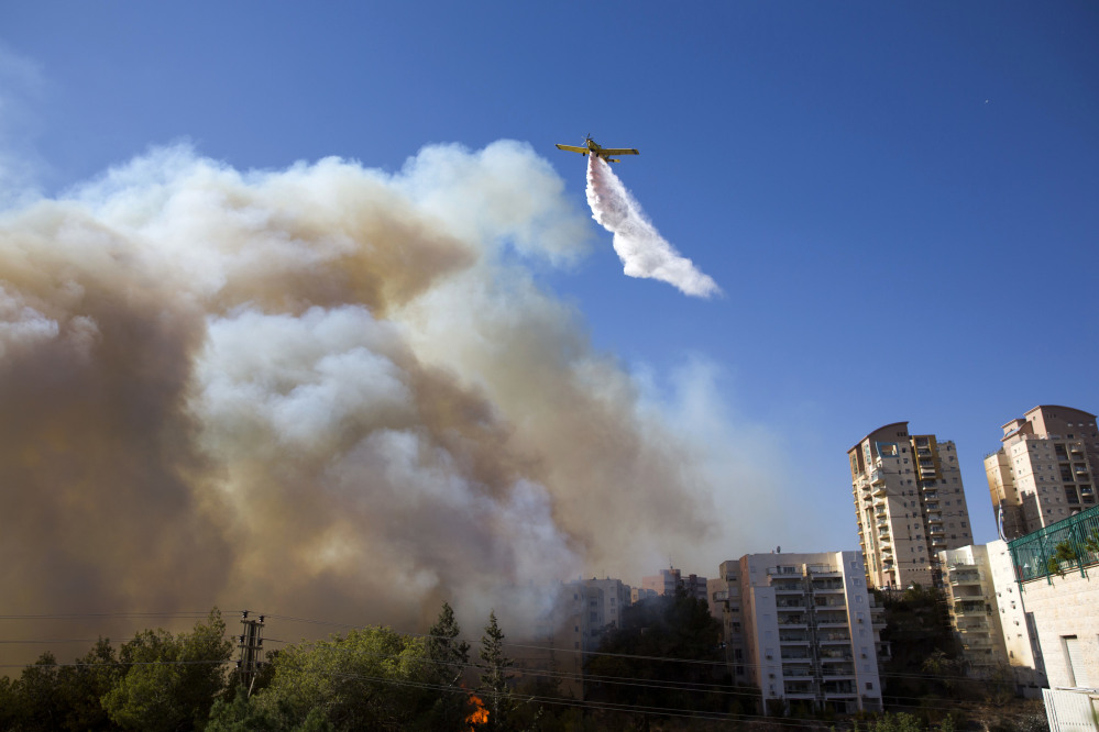 A plane flies over the wildfires in Haifa, Israel, on Thursday.
(AP Photo/Ariel Schalit)