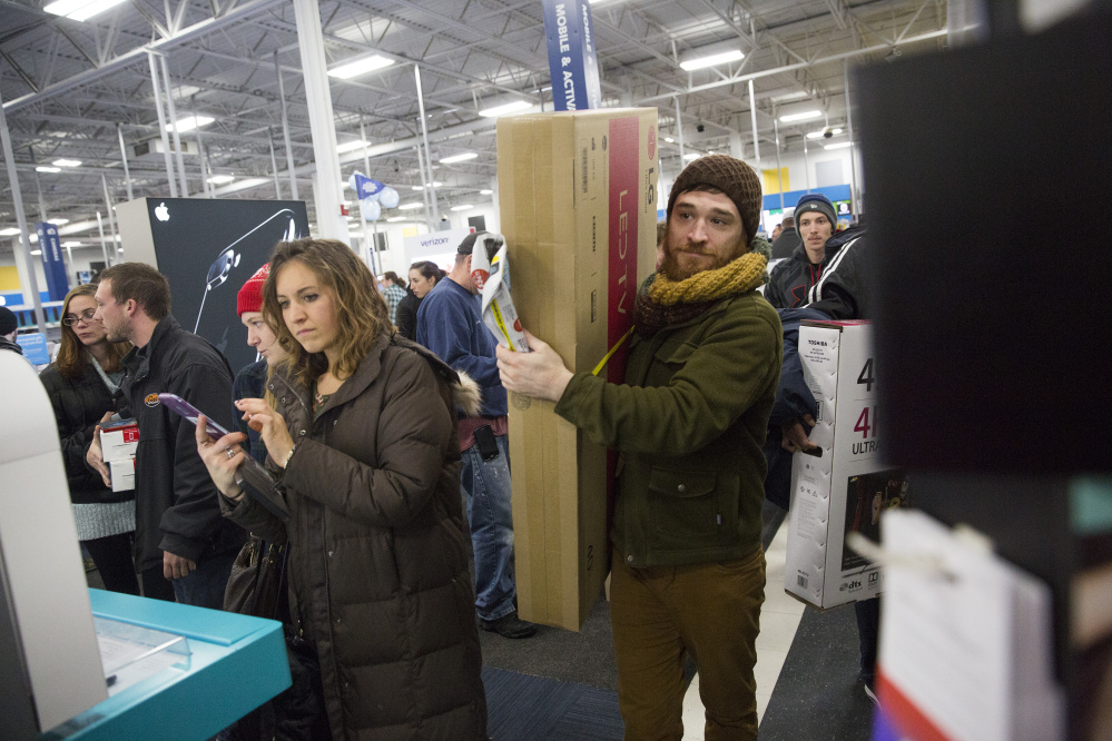 Andrew Moser of Portland carries a TV to the check-out line at Best Buy just after midnight Friday at the Maine Mall. Stores were awash in Black Friday shoppers, as retailers throughout Maine opened at midnight to lure customers with door-busting deals. The annual shopping extravaganza that extends into the weekend is the kickoff to a national holiday shopping season that analysts believe will top $1 trillion. (Brianna Soukup/Staff Photographer)