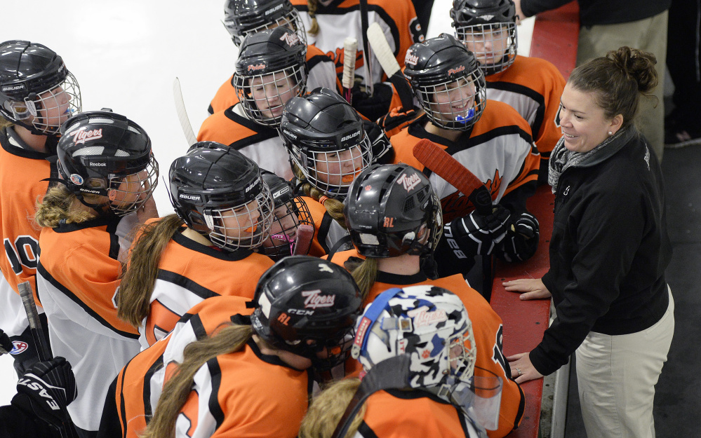 Biddeford Coach Ashley Potvin talks with her girls' hockey players, who are part of the team regardless of the rivalry in other sports. Of the 28 girls on the roster, 23 are from Biddeford and five from Thornton Academy in Saco.