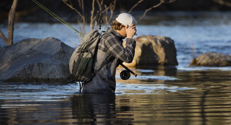 Tucker Van Dusen of Portland blocks the sun while fishing in the Presumpscot River earlier this month. Removing the Sappi dam will revive the ecosystem and open up fishing, he says.