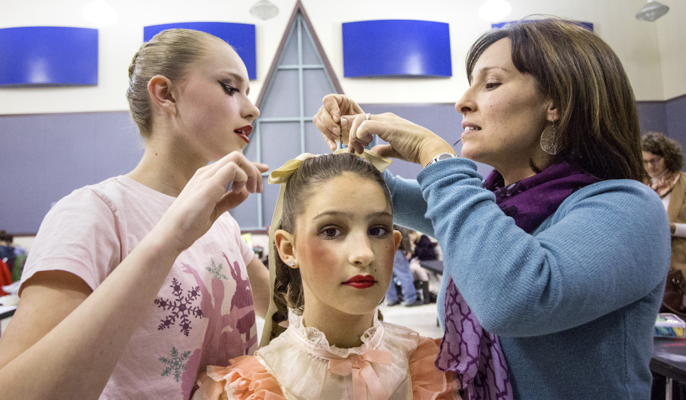 Eliza Albert, 11, of Scarborough holds still as her mom, Tricia Albert, right, and fellow dancer Ryleigh Raber, 13, of Falmouth attach a bow in Eliza's hair.