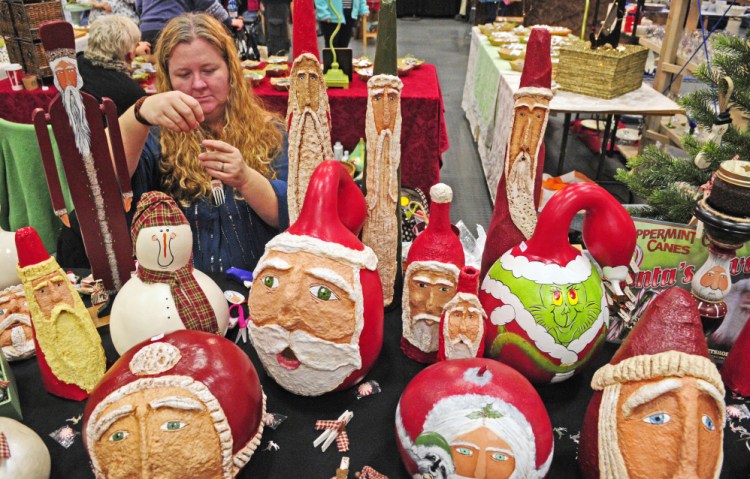 Jessica Howarth ties a string on a painted Santa fork ornament while waiting for customers during a craft show Saturday at the Augusta Civic Center. 