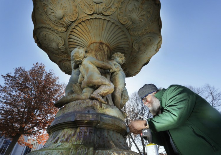 Jonathan Taggart, a sculpture restorer from Georgetown, works at loosening bolts on the fountain in Lincoln Park in Portland on Monday. The fountain sculpture, which was installed in 1871, will be removed Tuesday and Taggart will restore it over the winter.