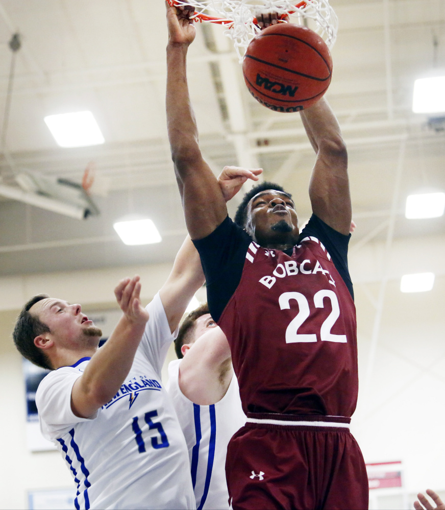 Malcolm Delpeche of Bates throws down a dunk after grabbing an offensive rebound while being defended by CJ Autry, left, and Zachary Kupferberg of UNE during the Bobcats' 71-68 win Monday in Biddeford.