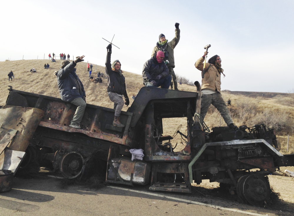 Protesters against the Dakota Access oil pipeline stand on a burned-out truck near Cannon Ball, N.D.,on Nov. 21. Hundreds have been arrested at the protest site.
