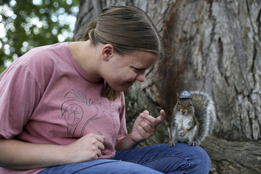 Penn State senior Mary Krupa plays with Sneezy the squirrel on Old Main Lawn in State College, Pa., in September.