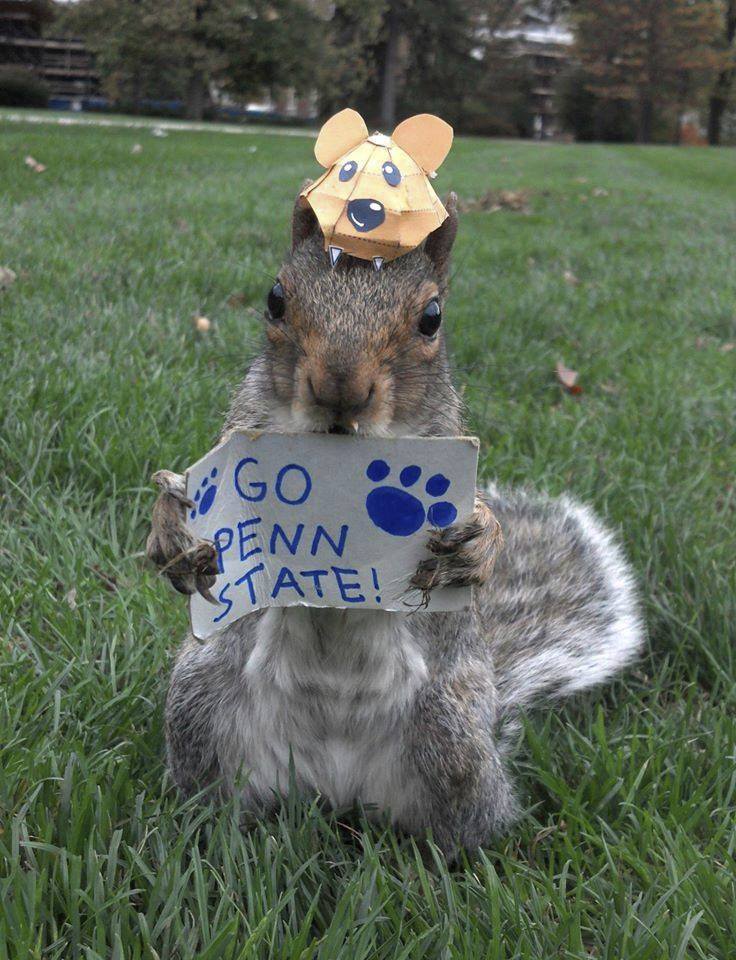 The current Sneezy, a squirrel that lives on the Penn State campus, wears a hat and holds a Go Penn State sign.