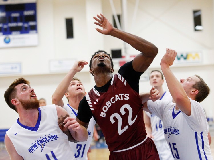 Malcolm Delpeche of Bates battles for position on a rebound with CJ Autry, right, and Zachary Kupferberg of UNE.