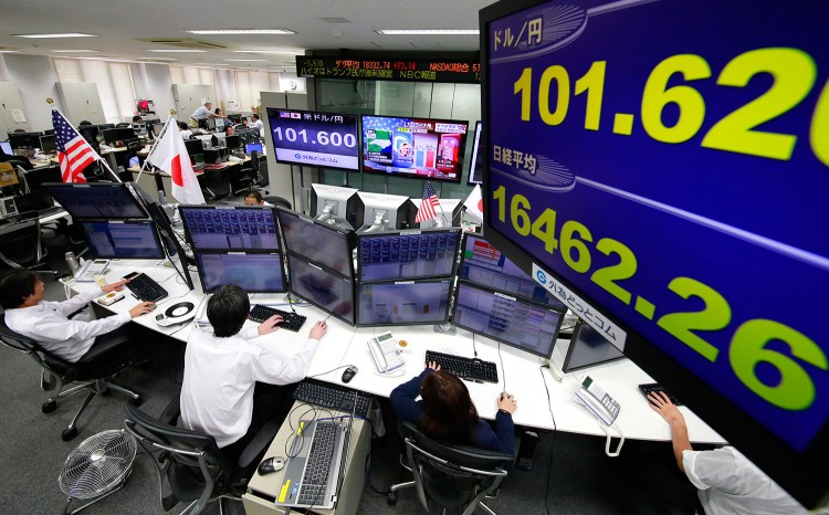 Money traders watch computer screens with the day's exchange rate between yen and the U.S. dollar at a foreign exchange brokerage in Tokyo on Wednesday. Asian markets tumbled as Donald Trump gained the lead in the electoral vote count in the presidential election.