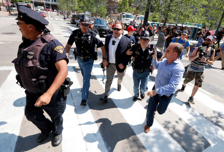 Alex Jones, center, a conspiracy theorist and radio show host, is escorted out of a crowd of protesters after he said he was attacked in Public Square on July 19, 2016, in Cleveland, during the Republican National Convention. 