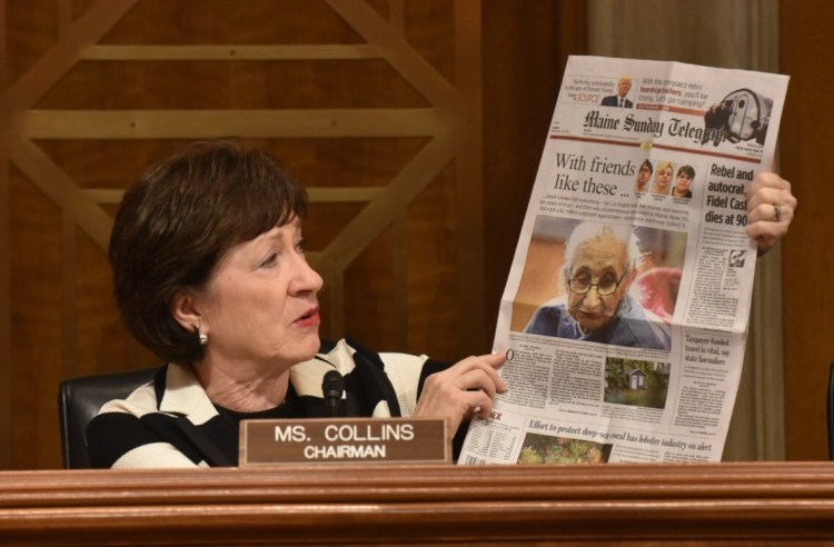 Sen. Susan Collins holds up the Nov. 27 edition of the Maine Sunday Telegram, which featured a story about a woman who lost her home and savings to a group of people who befriended her in California and drove her across the country, abandoning her in Maine. 